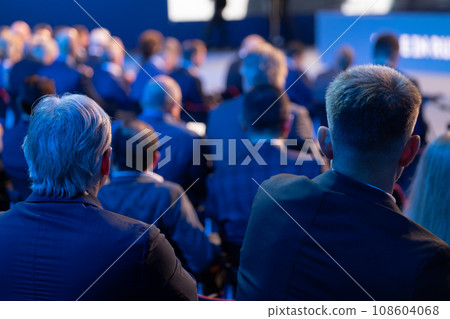 Back view of male business professionals attending conference meeting in auditorium at export forum  108604068