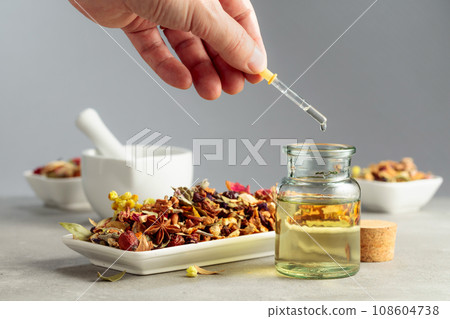 Dropping essential oil or herbal tincture into a glass bottle. Dropping essential oil or herbal tincture into a glass bottle. 108604738