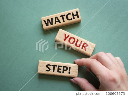 Watch your Step symbol. Concept words Watch your Step on wooden blocks. Businessman hand. Beautiful grey green background. Business and Watch your Step concept. Copy space. Watch your Step symbol. Concept words Watch your Step on wooden blocks. Businessman hand. Beautiful grey green background. Business and Watch your Step concept. Copy space. 108605673