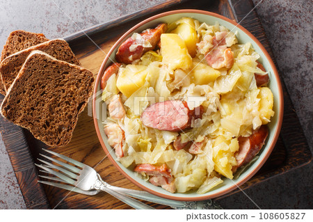 Hunter's cabbage stewed with sausage, potatoes, bacon and onions close-up in a bowl. Horizontal top view 108605827