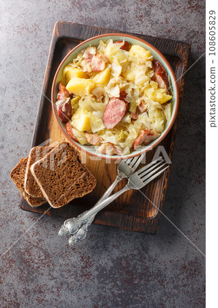 German Jager Kohl, hunter's cabbage with Sausage, Bacon and Potatoes close-up in a bowl. Vertical top view German Jager Kohl, hunter's cabbage with Sausage, Bacon and Potatoes close-up in a bowl. Vertical top view 108605829