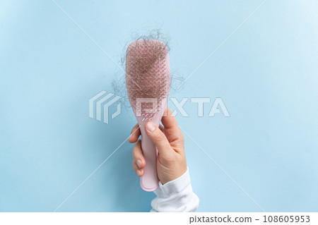 Hair loss concept - female hand holding brush with lost hair Hair loss concept - female hand holding brush with lost hair 108605953