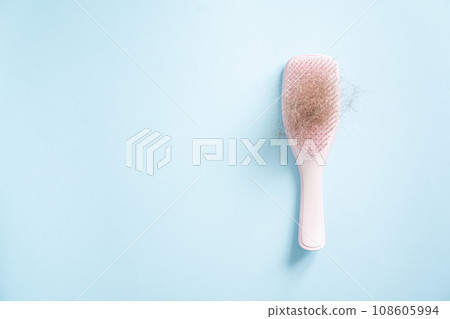 Hair loss concept - pink brush with lost hair on blue background 108605994