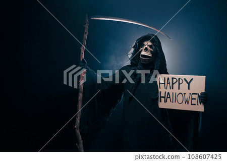 Skeleton, skull, silhouette of a man in a black robe, depicting death holding a happy halloween Skeleton, skull, silhouette of a man in a black robe, depicting death holding a happy halloween 108607425