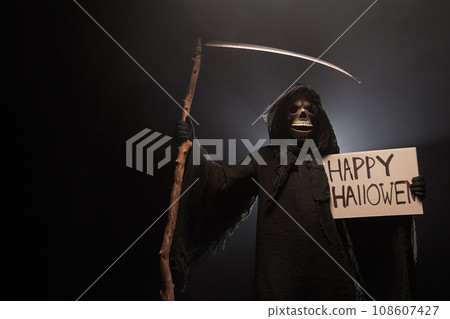 The scary grim reaper is holding a sign happy halloween poster . Death with poster. Skeleton, skull 108607427