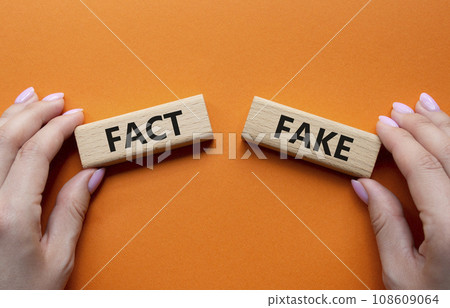 Fact or Fake symbol. Concept word Fact or Fake on wooden blocks. Businessman hand. Beautiful orange background. Business and Fact or Fake concept. Copy space 108609064