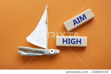 Aim High symbol. Wooden blocks with words Aim High. Beautiful orange background with boat. Business and Aim High concept. Copy space. 108609100