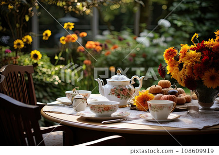 flowers and tea cups on a table in front of an open window with the sun shining through the trees behind 108609919