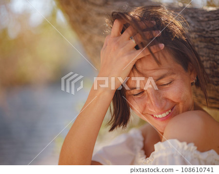Beautiful Asian young woman in white dress outdoor near olive tree. embracing fresh air and engaging in outdoor activities. Friluftsliv concept means spending as much time outdoors as possible 108610741