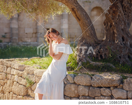 Beautiful Asian young woman in white dress outdoor. Acropolis of Rhodes Famous ruins of ancient settlement with various buildings such as stadium and theater. 108610751