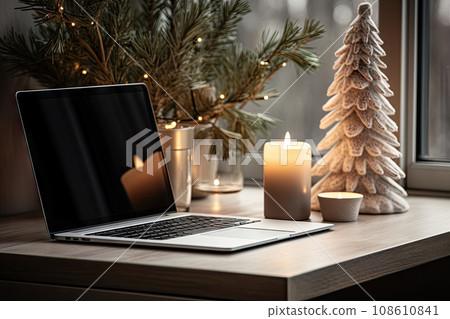 a laptop on a desk next to a christmas tree with candles and a lit candle in the window behind it a laptop on a desk next to a christmas tree with candles and a lit candle in the window behind it 108610841
