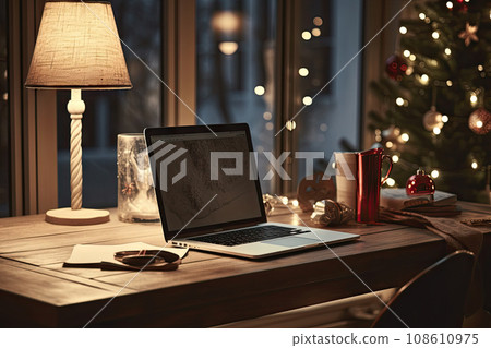 a laptop sitting on a desk next to a christmas tree with lights in the background and a cup of coffee 108610975