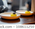 Yellow cheesecake dessert in white plate with black chocolate.  108611250