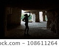 Silhouette woman holding daggers in cave exercising 108611264
