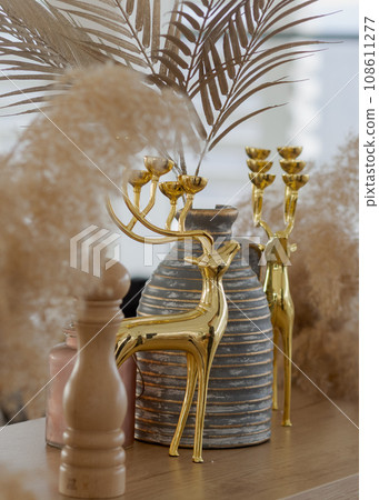 Golden deer decorative element with a gray stripped vase vertical. 108611277