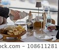 Sommelier pouring white wine into glasses with hidden bottle 108611281