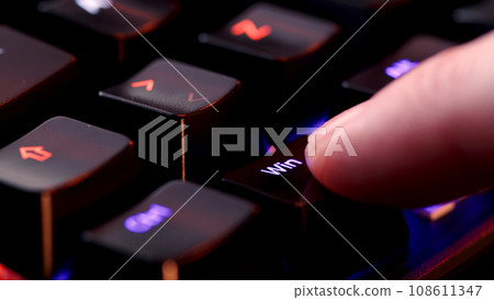 Human finger clicks on the Windows key on the computer keyboard, close up view. Man finger presses Win on the keyboard key, macro shot. Rgb led light keyboard Human finger clicks on the Windows key on the computer keyboard, close up view. Man finger presses Win on the keyboard key, macro shot. Rgb led light keyboard 108611347