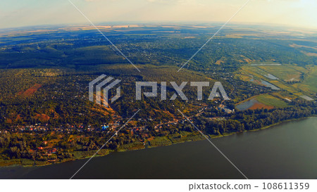 Photo from a drone of a beautiful summer landscape over the river. Beautiful summer landscape with a wide river and green coastline. Aerial photography of the suburban landscape. Photo from a drone of a beautiful summer landscape over the river. Beautiful summer landscape with a wide river and green coastline. Aerial photography of the suburban landscape. 108611359