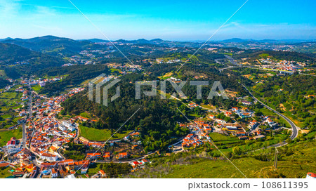 Drone view of a beautiful small European city with a beautiful hilly landscape on a summer day. Top view of a European village located in a valley with a beautiful green landscape. 108611395