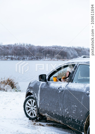 woman eat burger sitting in car at the frozen lake beach 108611694