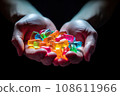 CBG Gummies. a person's hands holding small pieces of colored glass in their palms, with the light shining through them 108611966