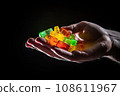 CBG Gummies. a person's hand holding several colored ice cubes in the image is on a black background and there are two fingers 108611967