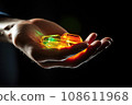 CBG Gummies. a person's hand holding an orange and green diamond in their palm, with the light shining through it 108611968