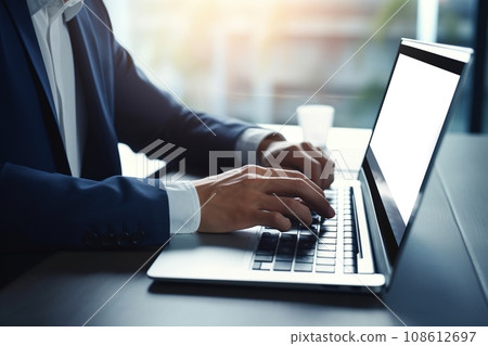 Image shows a close-up of a person in a business suit typing on a laptop with a blank screen 108612697