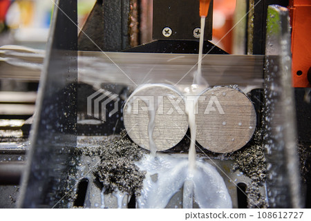 Close up scene the operation of band saw cutting machine cutting the metal shaft parts with coolant method. Close up scene the operation of band saw cutting machine cutting the metal shaft parts with coolant method. 108612727