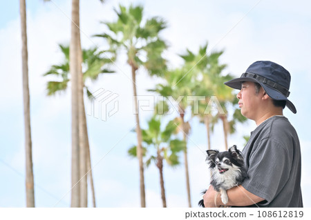 Male owner taking a walk with his Chihuahua in his arms - tropical resort image 108612819