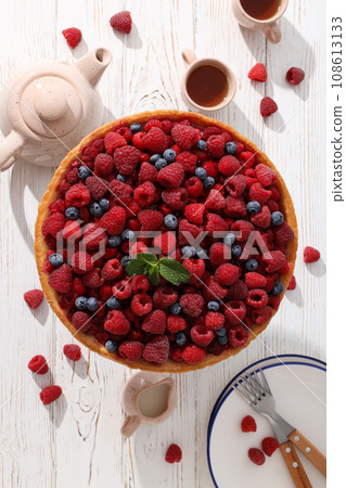 Berry pie, cups, teapot and plates on light wooden background, top view 108613133