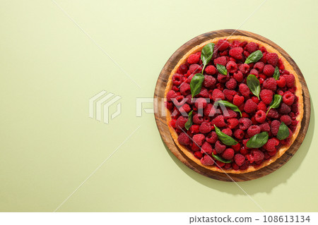 Berry pie on wooden plate on light green background, space for text Berry pie on wooden plate on light green background, space for text 108613134