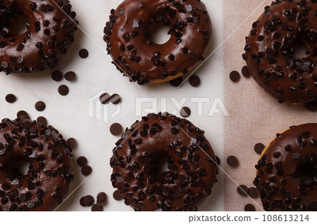 Chocolate donuts and chocolate chips on light background, top view Chocolate donuts and chocolate chips on light background, top view 108613214