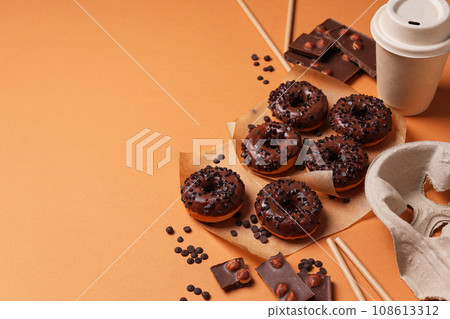 Chocolate donuts, chocolate and paper cup on orange background, space for text 108613312