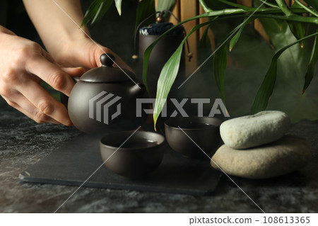 The concept of Asian tea, on a dark background with plants. The concept of Asian tea, on a dark background with plants. 108613365