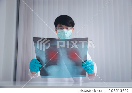 A doctor is diagnosing the results of the lung X-rays of patients infected with the coronavirus. The film shows symptom of corona virus infect patient lung and respiratory organ. A doctor is diagnosing the results of the lung X-rays of patients infected with the coronavirus. The film shows symptom of corona virus infect patient lung and respiratory organ. 108613792
