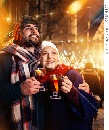 Lovely romantic couple having fun outdoors on fair and hugs while looking to sky on festive salute, fireworks in New Year night. 108614343