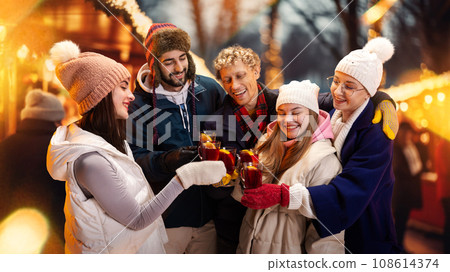 Group portrait of happy cheerful people in cozy fair atmosphere standing outdoor and clinking cup of hot warming drink. Group portrait of happy cheerful people in cozy fair atmosphere standing outdoor and clinking cup of hot warming drink. 108614374