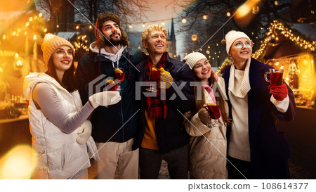 Group portrait of happy cheerful people, friends with cup of hot warming mulled-wine and enjoying moment before New Year Day. 108614377