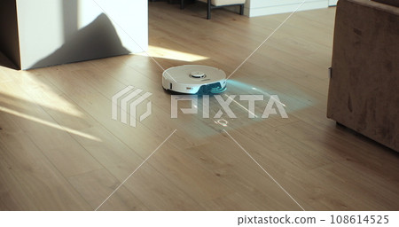 White robot vacuum cleaner scan laminate wood floor. Detectors help to recognize walls and objects and optimize cleaning. Smart futuristic cleaning device. Creates cleaning map. Technology concept White robot vacuum cleaner scan laminate wood floor. Detectors help to recognize walls and objects and optimize cleaning. Smart futuristic cleaning device. Creates cleaning map. Technology concept 108614525