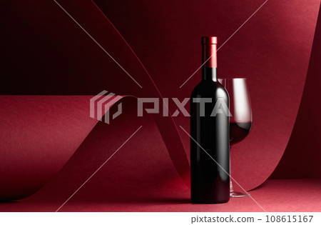 Bottle and glass of red wine on a red background. Bottle and glass of red wine on a red background. 108615167