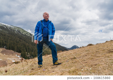 Man hiker enjoys snowdrops blooming at Carpathian mountains Man hiker enjoys snowdrops blooming at Carpathian mountains 108615860