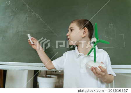 Kid shows and explains about wind generator model at school 108616567