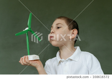 Kid shows and explains about wind generator model at school 108616572