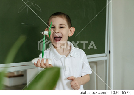 Kid shows and explains about wind generator model at school 108616574