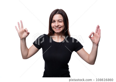 Positive pretty young brunette woman wearing a black t-shirt showing ok gesture 108616860