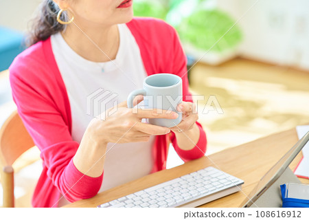 Hand of a senior woman holding a mug 108616912