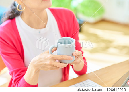 拿著杯子的一位資深婦女的手 拿著杯子的一位資深婦女的手 108616913
