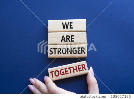 We are stronger together symbol. Wooden blocks with words We are stronger together. Businessman hand. Beautiful deep blue background. We are stronger together concept. Copy space. 108617330