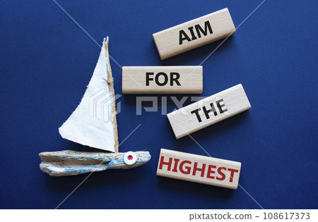 Aim for the Highest symbol. Concept words Aim for the Highest on wooden blocks. Beautiful deep blue background with boat. Business and Aim for the Highest concept. Copy space. Aim for the Highest symbol. Concept words Aim for the Highest on wooden blocks. Beautiful deep blue background with boat. Business and Aim for the Highest concept. Copy space. 108617373
